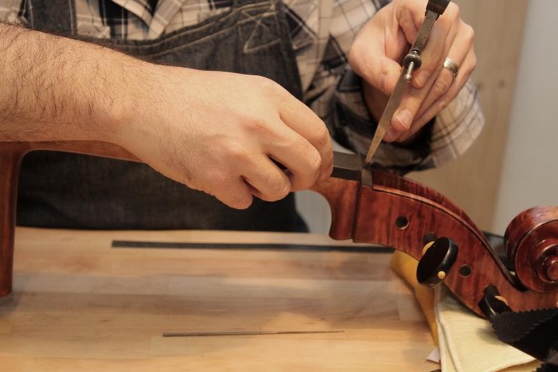 Geigenbauer richtet ein Instrument in der Werkstatt ein